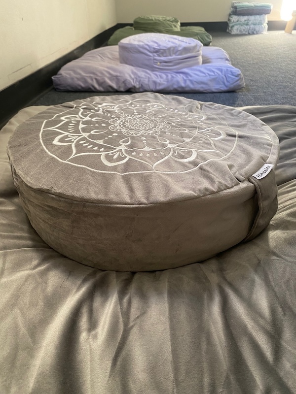 A round pillow on a meditation/prayer cushion